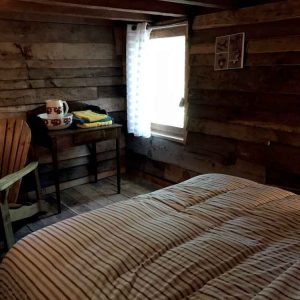 Chalet en bois au Limousin, intérieur chaleureux avec lit douillet et fauteuil en bois.
