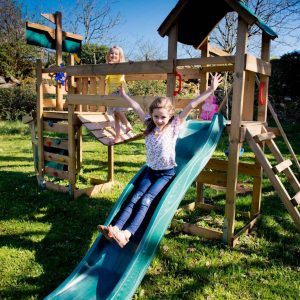 Hébergement insolite à Midi-Pyrénées : cabane en bois avec toboggan et enfants joyeux.