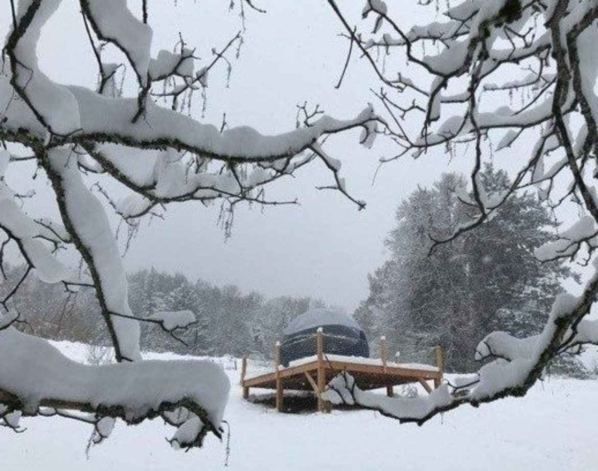 Hébergement insolite en Auvergne : yourte sur plateforme, entourée de neige.