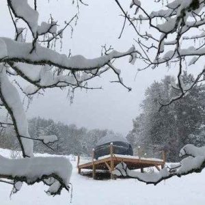 Hébergement insolite en Auvergne : yourte sur plateforme, entourée de neige.