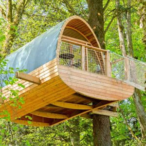 Cabane perchée en bois dans les arbres, entourée de verdure luxuriante.