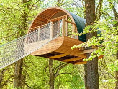 Cabane perchée en bois dans les arbres, entourée de verdure luxuriante.