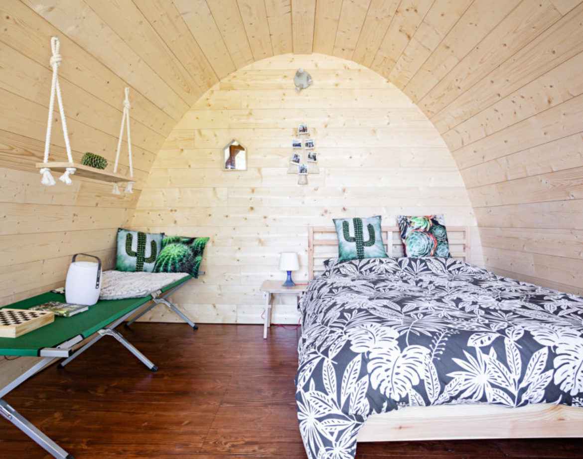 Hébergement insolite en forme de cabane avec intérieur en bois et décor tropical.