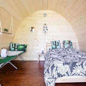 Hébergement insolite en forme de bulle en bois, décor tropical et lit confortable.