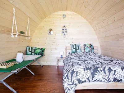 Hébergement insolite en forme de bulle en bois, décor tropical et lit confortable.