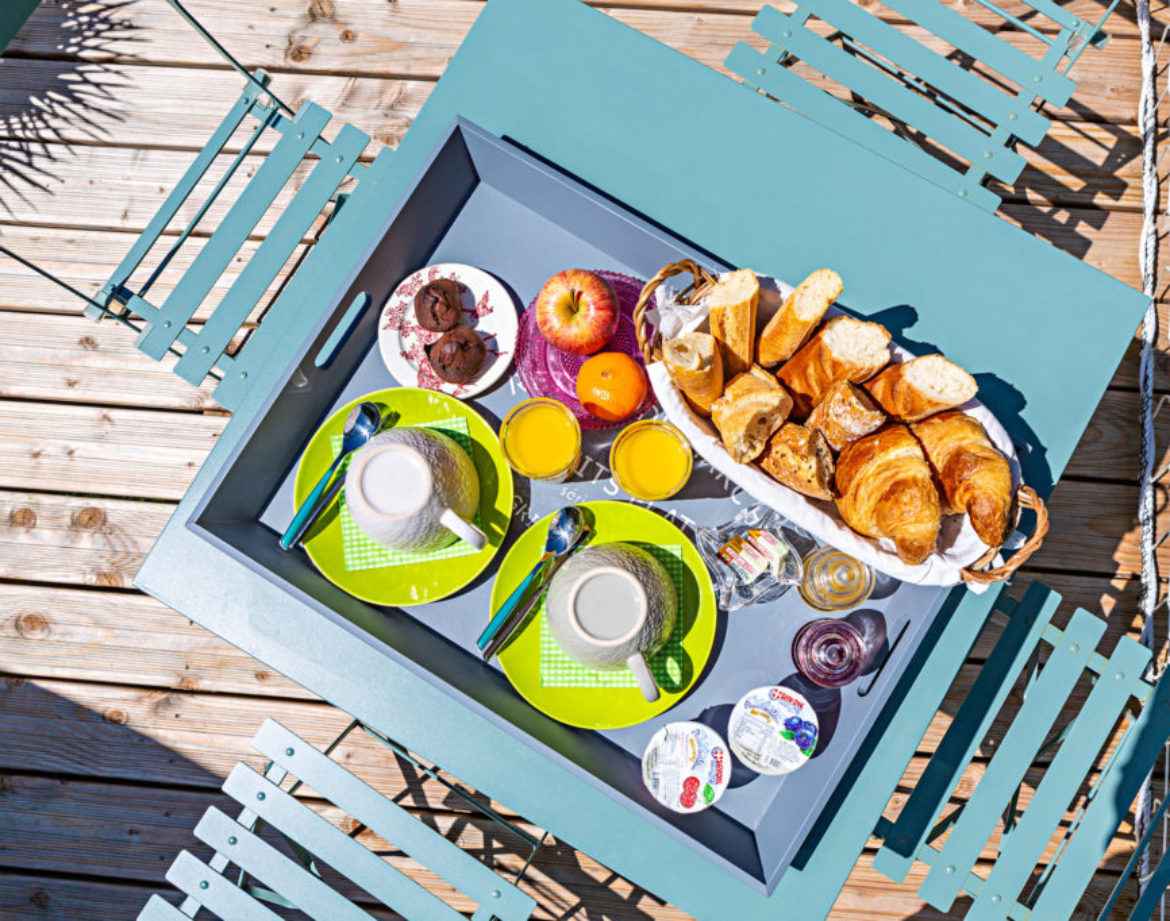 Petit-déjeuner gourmand servi sur une terrasse en bois, hébergement insolite en Auvergne.