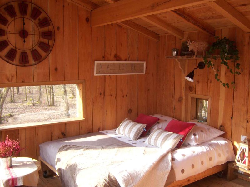 Chalet en bois chaleureux avec lit douillet et décoration naturelle.
