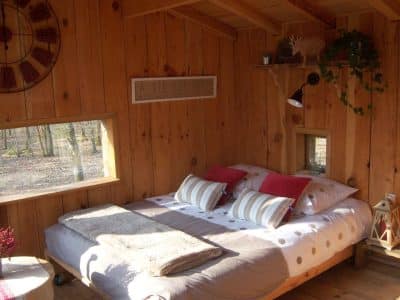 Cabane en bois avec lit douillet et décoration chaleureuse en Aquitaine.