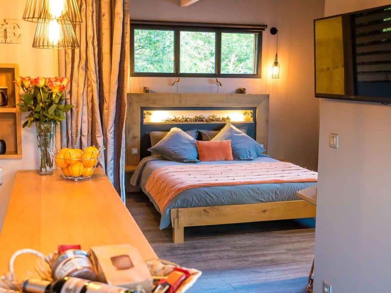 Chambre dhôtes moderne avec lit douillet et éclairage chaleureux.