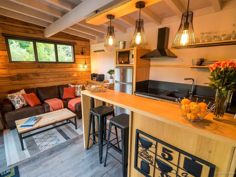 Chalet moderne avec cuisine équipée et salon cosy, éclairé par des suspensions design.