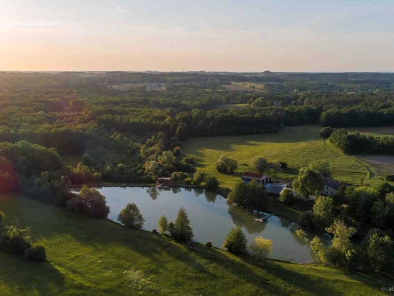 Gîte rural avec vue sur un étang, entouré de verdure et de paysages paisibles.