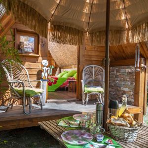 Hébergement insolite en cabane avec terrasse ombragée et décor chaleureux.
