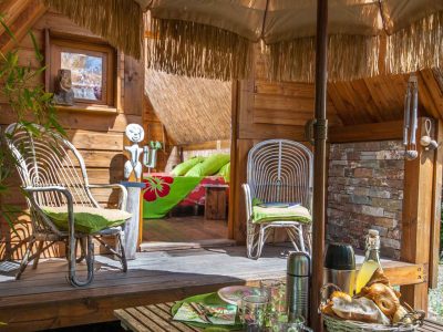 Hébergement insolite en cabane avec terrasse ombragée et décor chaleureux.