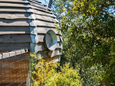 Cabane en bois avec une fenêtre ronde, nichée parmi la verdure en Provence-Alpes-Côte dAzur.