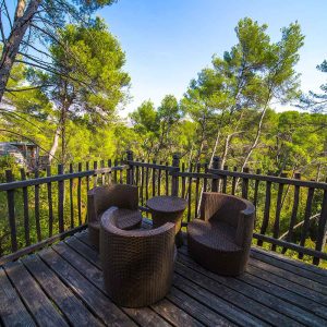 Terrasse en bois avec fauteuils en rotin, vue sur la nature en Provence-Alpes-Côte dAzur.