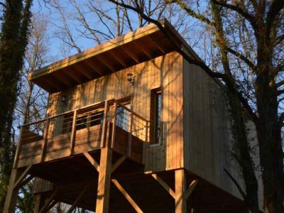 Cabane perchée en bois dans les arbres, offrant une vue imprenable sur la nature.