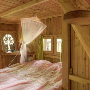Cabane en bois à Champagne-Ardenne, lit douillet sous un voile délicat.