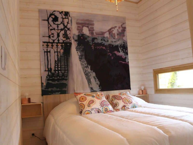 Chambre dhôtes moderne avec lit double et œuvre dart colorée au mur.