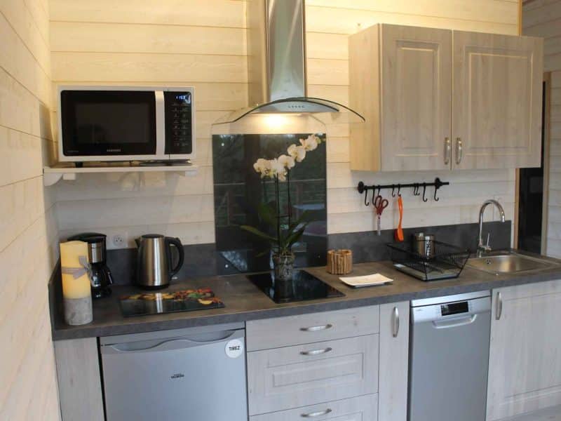 Cuisine moderne dun chalet en bois, équipée dun micro-ondes et dun évier.