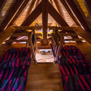 Chalet en bois avec lits colorés, vue sur un espace chaleureux et accueillant.