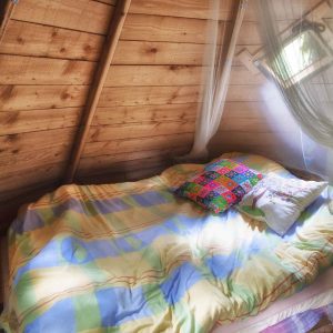 Cabane en bois à Champagne-Ardennes, lit douillet avec coussins colorés.