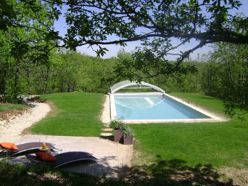 Villa avec piscine extérieure, entourée de verdure et chaises longues confortables.