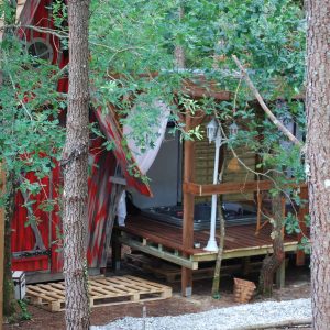 Cabane perchée en Aquitaine, entourée darbres, avec terrasse et jacuzzi.