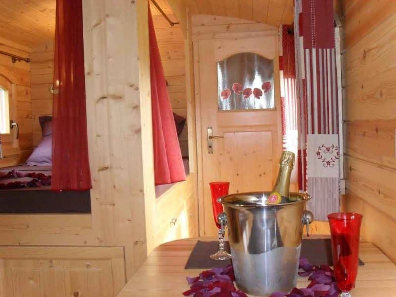 Chalet en bois chaleureux avec champagne et pétales de rose sur la table.