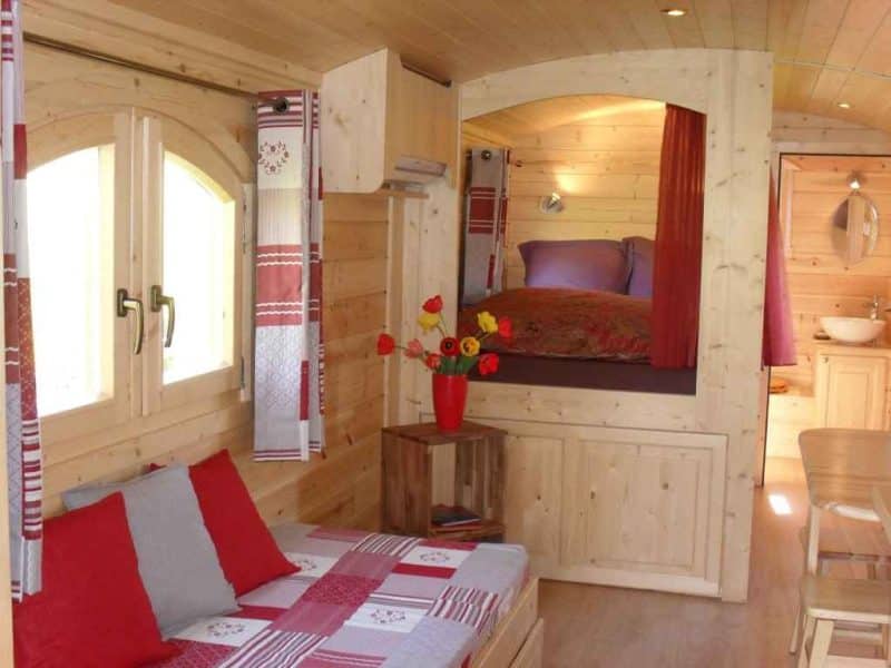Chalet en bois chaleureux avec lit douillet et décor coloré. Parfait pour un séjour relaxant.