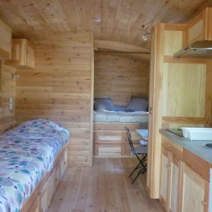 Cabane en bois à Languedoc-Roussillon, intérieur chaleureux avec lits et cuisine équipée.