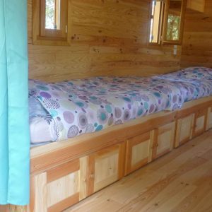 Chalet en bois avec lit douillet et décor chaleureux à Languedoc-Roussillon.