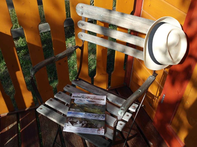 Chaise en bois avec chapeau et brochures, ambiance chaleureuse dun gîte.