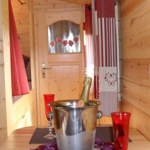 Cabane en bois romantique avec bouteille de champagne et décor fleuri.