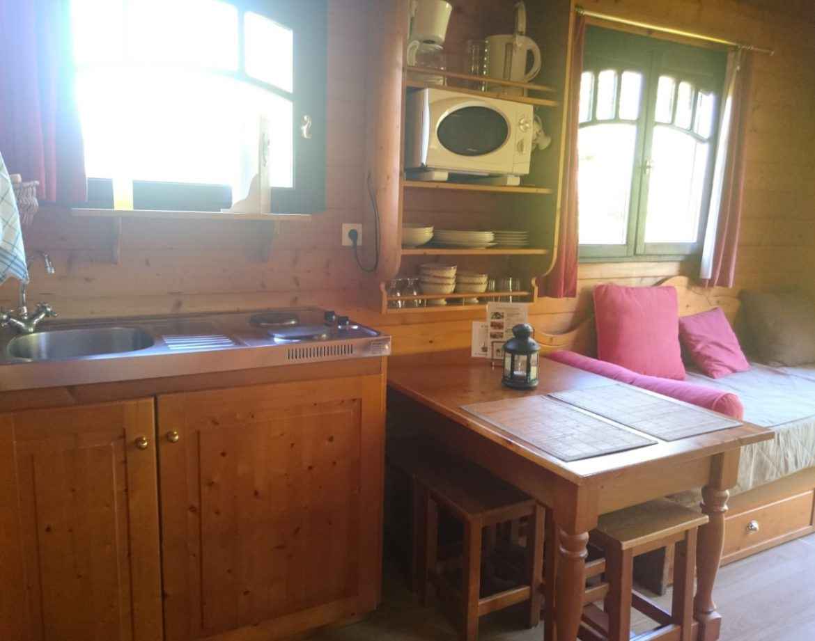 Cabane en bois cosy avec kitchenette et coin repas lumineux. Parfait pour un séjour unique.