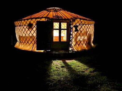 Yourte lumineuse en Auvergne, illuminée la nuit, offrant une ambiance chaleureuse.