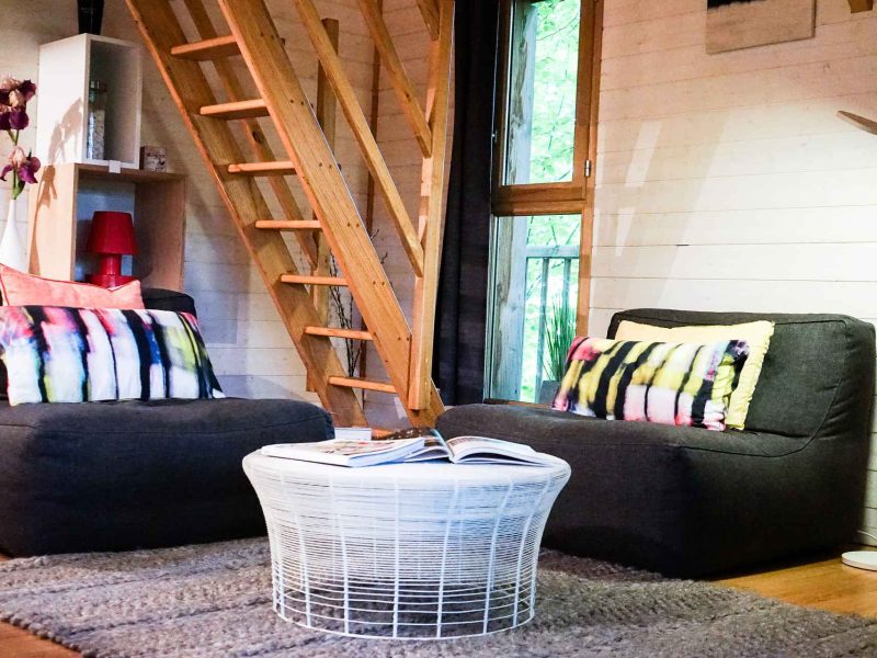 Chalet cosy avec fauteuils colorés et une belle lumière naturelle.