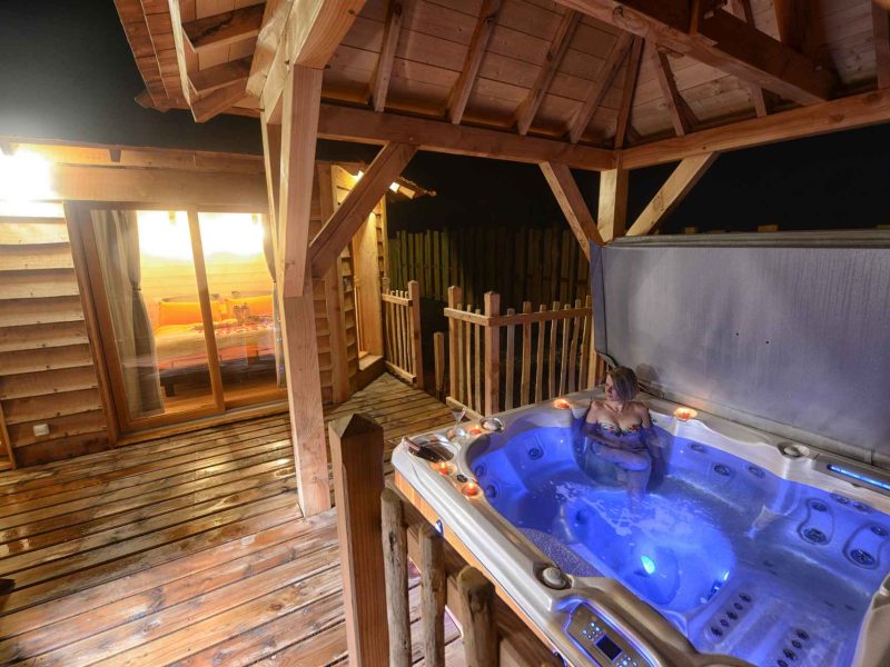Chalet en bois avec jacuzzi extérieur, offrant une vue nocturne apaisante.