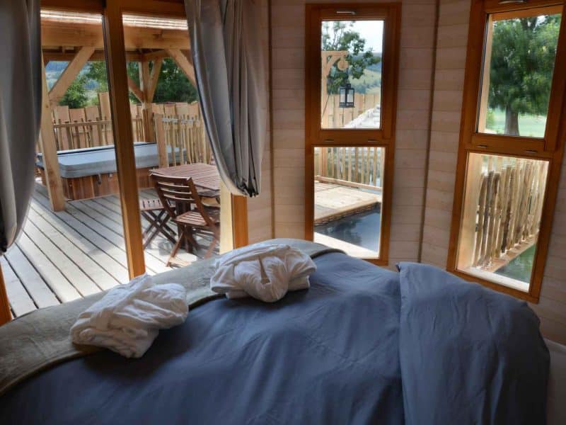 Chalet cosy avec vue sur la terrasse et jacuzzi, ambiance chaleureuse et relaxante.