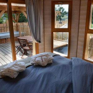 Cabane en bois avec vue sur la terrasse et jacuzzi, ambiance chaleureuse.