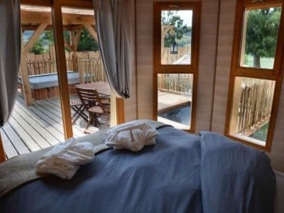 Cabane en bois avec vue sur la terrasse et jacuzzi, ambiance chaleureuse.
