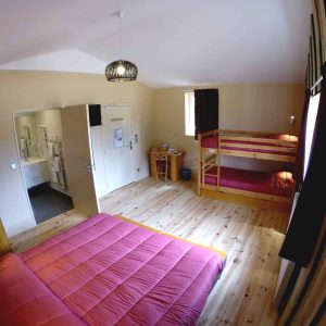 Chambre familiale en bois avec lit double et lits superposés, ambiance chaleureuse.