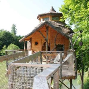 Cabane dans les arbres au cœur de la nature, avec une passerelle en bois.