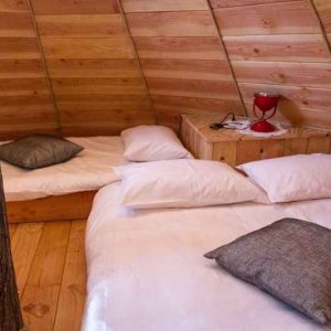 Hébergement insolite en bois avec lits douillets et lampe rouge décorative.