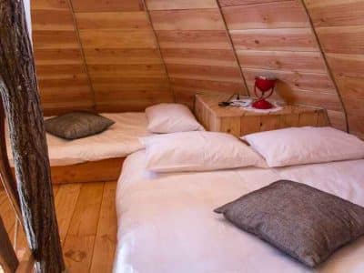 Hébergement insolite en bois avec lits douillets et lampe rouge décorative.