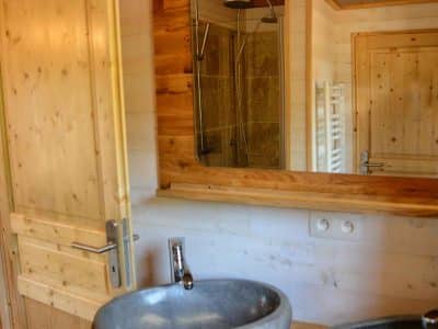 Salle de bain en bois avec vasques en pierre dans un hébergement insolite en Auvergne.