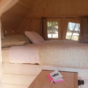 Cabane en bois cosy en Bretagne, lit douillet et lumière naturelle.