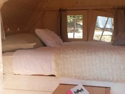 Cabane en bois cosy en Bretagne, lit douillet et lumière naturelle.