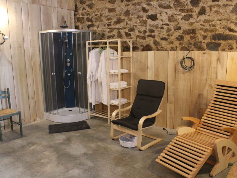 Hébergement de type gîte avec douche moderne et coin détente en bois.