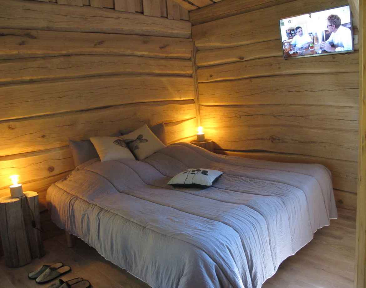 Chalet en bois chaleureux avec lit douillet et ambiance lumineuse apaisante.
