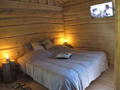 Chalet en bois chaleureux avec lit douillet et ambiance lumineuse apaisante.